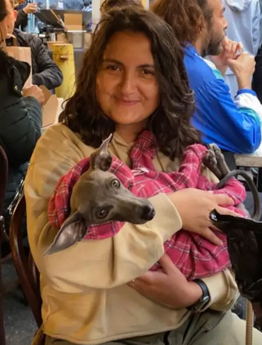 Sophia in a park, looking to camera whilst happily holding a dog